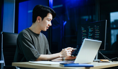 young male programmer working with tablet and screen displaying code. modern tech office setup, grea