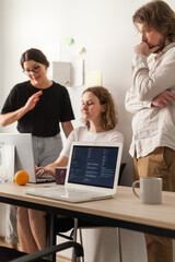 three software developers brainstorming in a modern office. team coding session with laptops showing