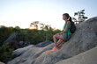© bilanol - Lonely woman hiker sitting alone on rocky mountain top enjoying view of morning nature on wilderness trail. Active lifestyle concept