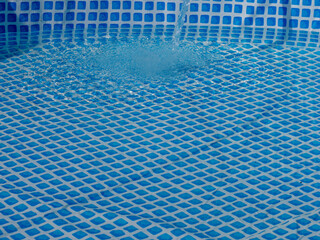 Poster - A pool with a blue tile floor and a blue water splashing out of the pool