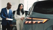 © wedmoments.stock - A car dealer in a modern car dealership advises a customer on buying or leasing a new car. The concept of an expensive purchase or lease of a modern car.