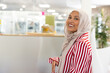 © WavebreakMediaMicro - Woman wearing hijab and striped blazer tapping office chair in open-plan office, copy space