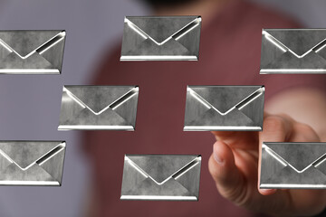 Abstract image of a man interacting with floating metallic email icons, representing digital communication and messaging.