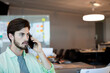 © WavebreakMediaMicro - Office worker placing call on smartphone at open-plan desk beside glass partition with sticky notes
