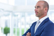 © WavebreakMediaMicro - Corporate professional standing and crossing arms in modern office lobby, with glass windows