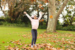 © wavebreak3 - African American girl wearing pink jacket and hat standing in park under tree, surrounded by leaves