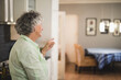 © WavebreakMediaMicro - Senior woman pointing toward dining space in kitchen, showing olive oil, checkered tablecloth