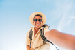 © Davide Angelini - Handsome young man taking selfie with smart mobile phone outdoors - Cheerful man smiling at camera on blue sky - Happy tourist enjoying summer vacation - People and technology concept