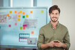 © WavebreakMediaMicro - Businessman holding smartphone and standing at whiteboard in office with sticky notes and charts