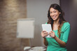 © WavebreakMediaMicro - Woman holding white tablet, smiling at camera in training room with flip chart, papers, copy space