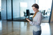 © WavebreakMediaMicro - Professional woman standing in office lobby holding tablet in striped top and trousers, copy space