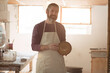 © WavebreakMediaMicro - Middle-aged potter wearing apron holding freshly thrown clay bowl near workbench in pottery studio