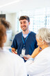© unai - Smiling nurse taking notes while talking with medical team in hospital