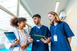 © unai - Medical team discussing patient's diagnosis using tablet and x ray in hospital corridor