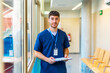 © unai - Young nurse holding medical records in hospital corridor