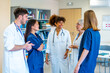 © unai - Medical team discussing patient care in hospital corridor