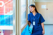 © unai - Young doctor looking out window, contemplating in hospital corridor