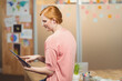 © WavebreakMediaMicro - Woman sitting on edge of desk at office interacting with tablet computer beside potted plant
