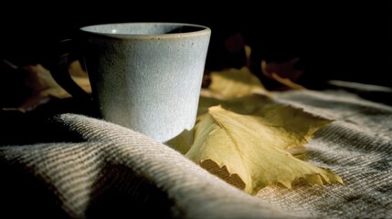 Poster - Ceramic Cup Resting on Linen Cloth With Fallen Leaf During Soft Natural Light