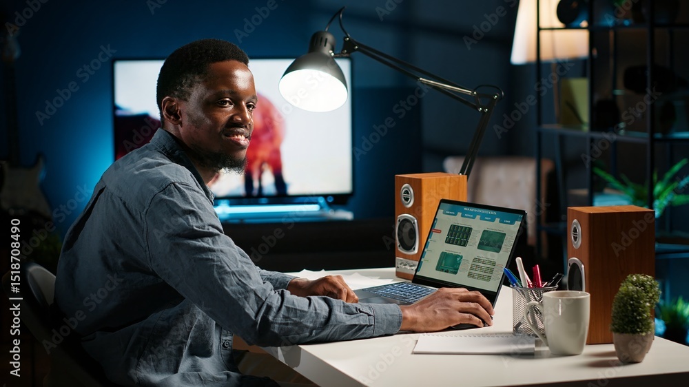 Black accountant working on monthly revenue balance on laptop at home ...