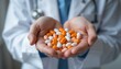 © Pungkas - Close up of medical professional holding a variety of orange and white capsules in both hands as a symbol of healthcare and medication