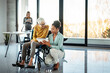 © NDABCREATIVITY - Diverse business colleagues collaborating. Woman in wheelchair working in inclusive office, teamwork