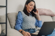© Ljustina - Smiling freelancer working from home on sofa with laptop and phone