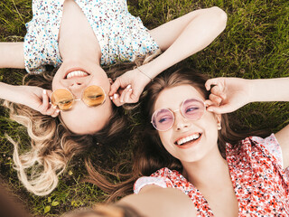 two young beautiful smiling hipster female in trendy summer sundress.sexy carefree women lying on th