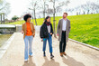 © Koldo_Studio - Three young professionals enjoy a conversation while walking together on a path in a sunny city park