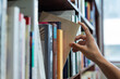 © Smallroombigdream - right hand choosing and picking book in public library.