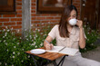 © Wasana - A woman sits at a table with a notebook and a cup of coffee