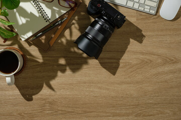 Wall Mural - Photographer’s creative desk setup with camera gear, planner, coffee, and natural plant shadows.