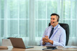 © BESTIMAGE - A doctor wearing a headset is sitting at his desk and talking to a patient via video call.