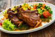 © Jacek Chabraszewski - Baked veal chops, boiled potatoes, green peas and carrots on wooden table