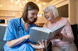 © zinkevych - Female care assistant reading a book to a elderly lady and both looking enjoyed