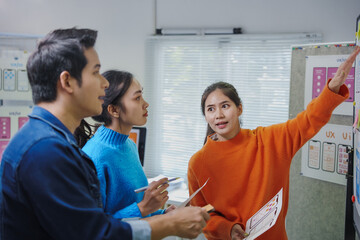 young creative team of asian ux ui designers working together discussing mobile app interface wirefr