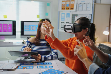 asian uiux web designers testing a virtual reality app in the office, wearing vr headsets and collab