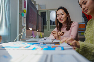 two female web designers collaborating on user interface design during a meeting in a modern office,