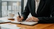 © Vyatcheslav - Businesswoman writing in notebook while sitting at desk with coffee