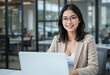 © Roshan - Smiling Asian Businesswoman with Laptop in Modern Office
