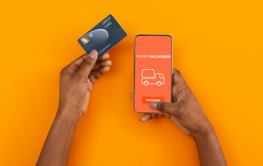 Fototapete - Stay at home, pay with credit card. African american man ordered with online app on cell phone, yellow background