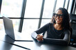 © Dorde - Young Asian Professional Woman In Black Attire Smiling While Working On Laptop In Modern Office