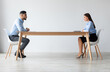 © Prostock-studio - Interview, Business Meeting Concept. Profile side view of two serious people in formalwear sitting in front of each other at long desk in the office while discussing something, hr hiring staff