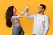 © Prostock-studio - Portrait Of Happy Young Arab Couple Giving High Five To Each Other, Cheerful Middle Eastern Man And Woman Enjoying Teamwork, Celebrating Common Success While Standing Over Yellow Studio Background