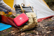 © Василь Івасюк - Red first aid kit on a backpack near a camping tent. Injuries and damage in the forest. Concept of medical support on a walk. Emergency assistance in case of injury on the trip a set of medicine