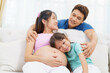 © DG PhotoStock - Happy Asian family with father, pregnant mother and daughter stay together in linving room.