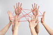 © Westend61 - Hands connected by red string symbolizing teamwork and networking
