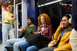 © Oscar - Young people using smartphones and headphones on subway train