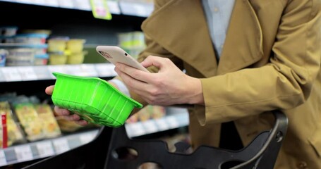 Man scanning product bar code in the shop using mobile phone app. Digital shopping future gadget consumerism concept.