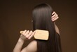 © New Africa - Teenage girl brushing her healthy long hair on brown background